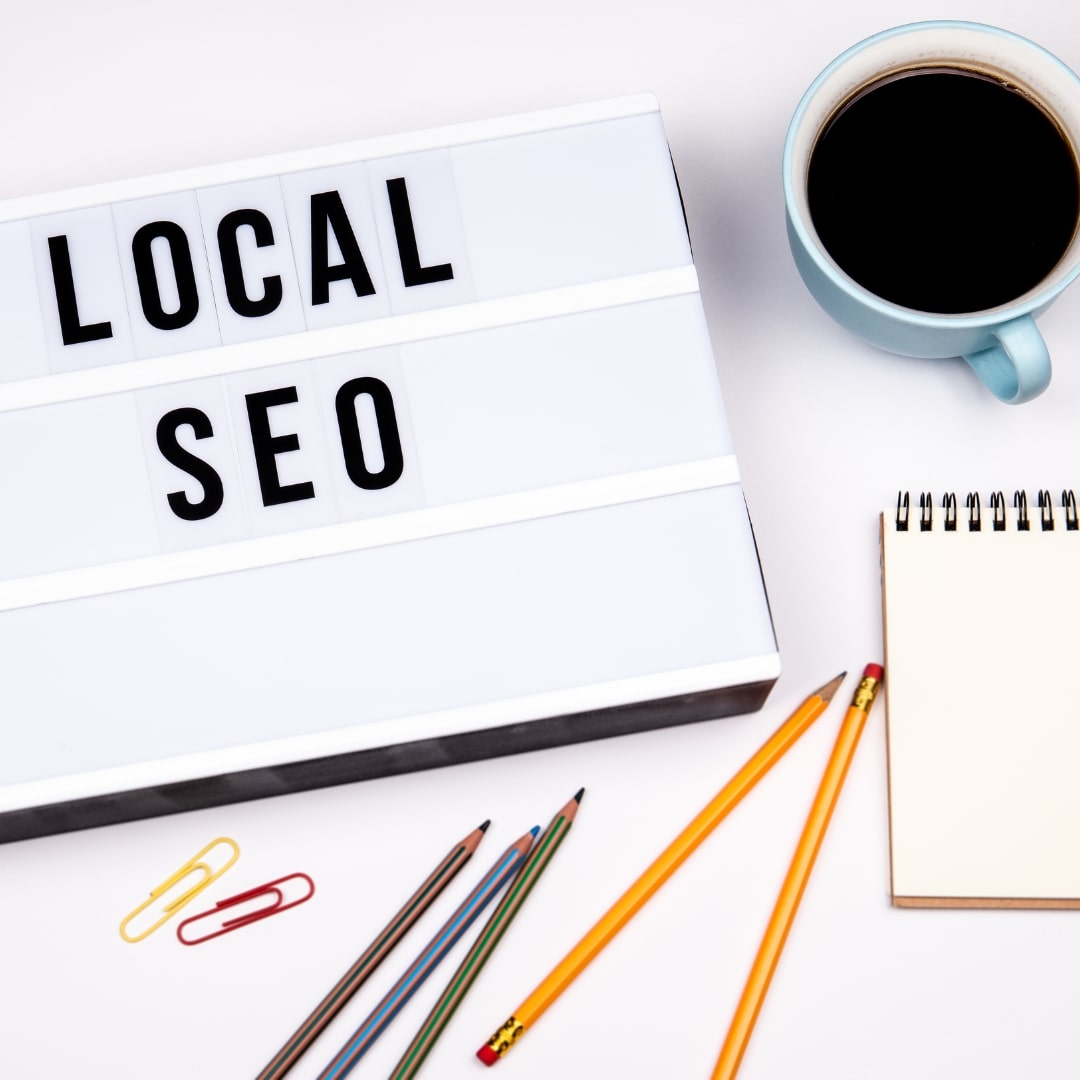 Flatlay of a lightbox displaying 'LOCAL SEO' with a cup of coffee, a notepad, and pencils.