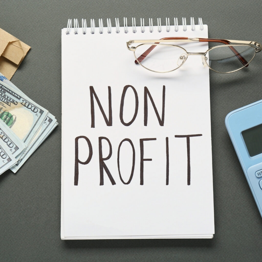 Notepad with “Non Profit” text beside glasses and money, illustrating budget-conscious Nonprofit SEO Ranking Factors.